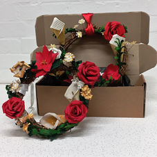 A photo showing two Christmas wreaths of paper flowers in a box.
