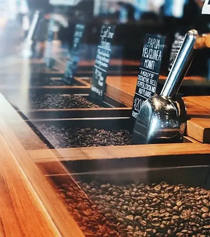 Bag of green coffee beans with loose beans displayed around it on a wooden surface.