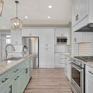 Galley kitchen with white upper cabinets, mint green lower cabinets, stainless steel appliances, and pendant lighting.