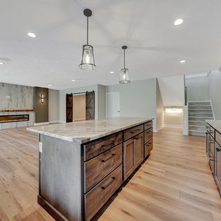 Murray Custom Homes kitchen with dark wood cabinets, marble island, hardwood floor, and a living room with fireplace.