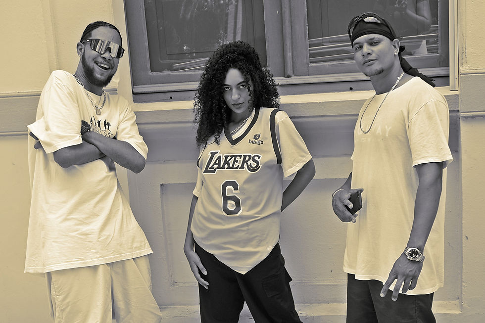 Três pessoas posam em frente a uma janela. A pessoa do meio veste uma camisa dos Lakers. Eles exibem expressões confiantes.