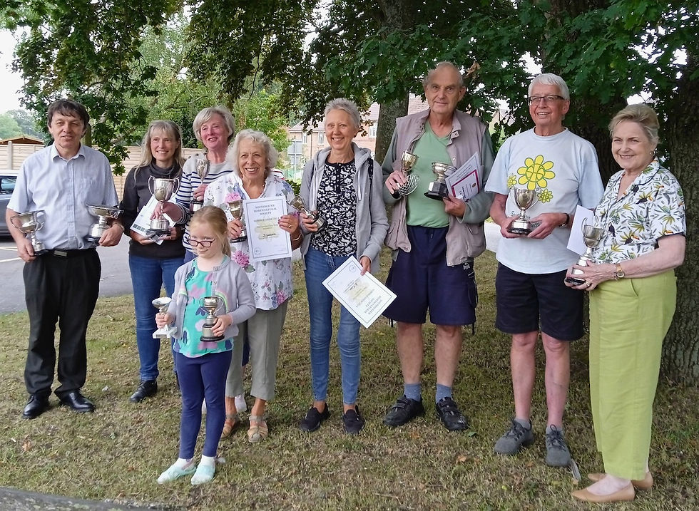 9 people standing with their trophies and certificates. Men and women and one child.