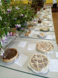 Long, white table with different cakes.