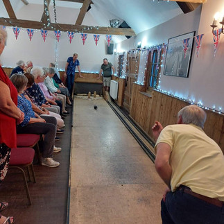 Indoor Play. Audition sitting on chairs on the left side of the photo. Foreground shows a player in action. Fairy lights, British flags and wooden beams for decoration.