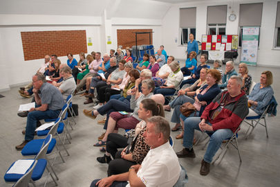A large group of people sitting down, watching a presentation.