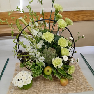 White and green flowers arranged in a basket.