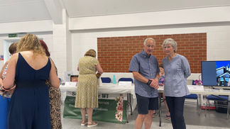 Groups of people chatting to each other in a hall, in front of stalls.