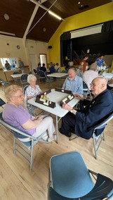 Elderly people sitting around a table playing a board game.