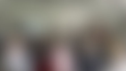 A person presents to a seated audience in a bright room. A screen displays "Southwater Neighbourhood Wardens." Attentive and engaged mood.