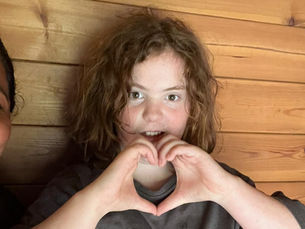 Young person makes a heart shape with their hands