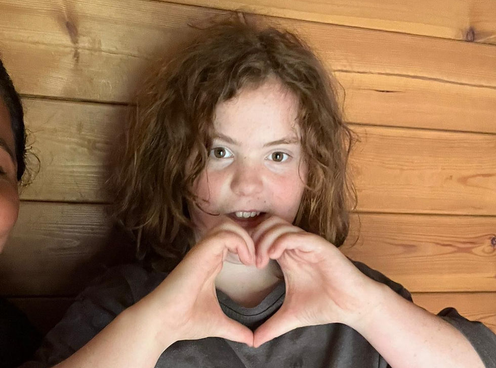 Young person makes a heart shape with their hands