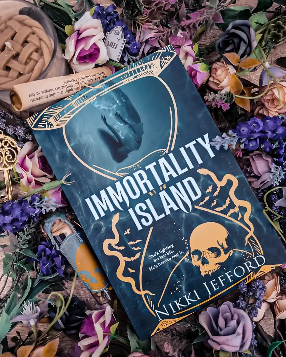 Book "Immortality Island" by Nikki Jefford lies on a floral background with purple and pink roses. A skull illustration is on the cover.