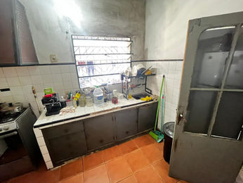 Cocina con gabinetes, ventana y puerta; múltiples objetos en el mostrador. Estudio Müller.
