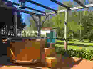jacuzzi in a garden under a wooden pergola