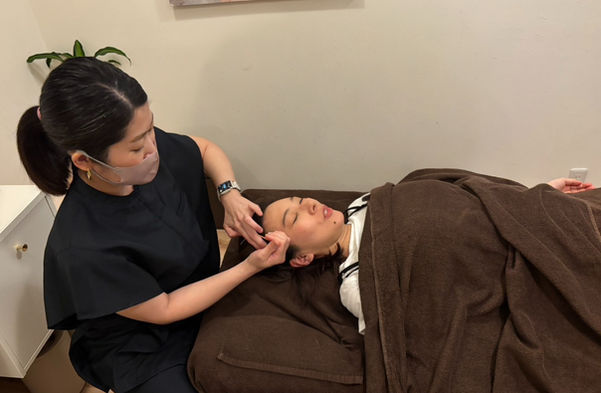仰向けになって会話をしながら、美容鍼を受けている