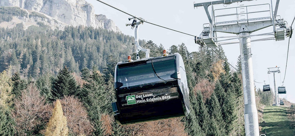 Seilbahnkabine über Nadelwald vor Felsberg; Aufdruck Der Loser. Mein Erlebnis Berg.