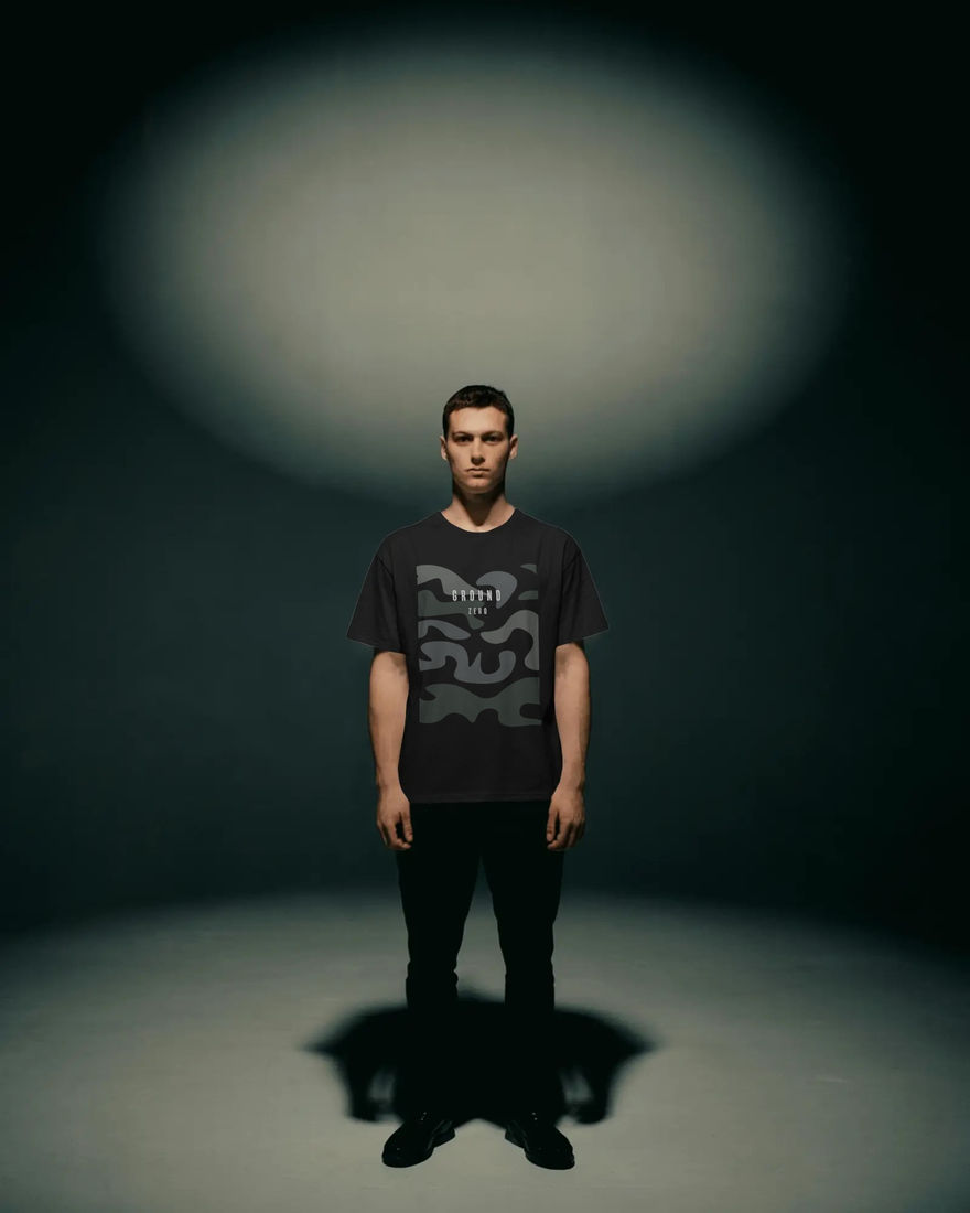 Person wearing graphic tee standing in studio with spotlight. LUXR.