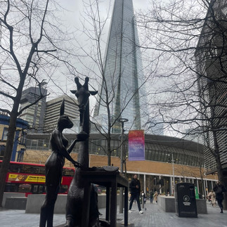 grey skies, man walking big buulding in the back. giraffe statue and rabit