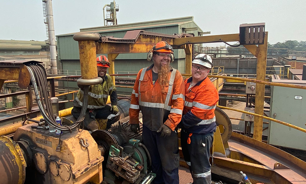 - Large crane lifts object at industrial site with gantry structure, pipes, and safety barriers.