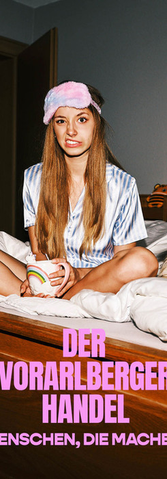 Teenager sitting on bed, wearing a sleeping mask and holding a coffee mug, funny cat near to her.