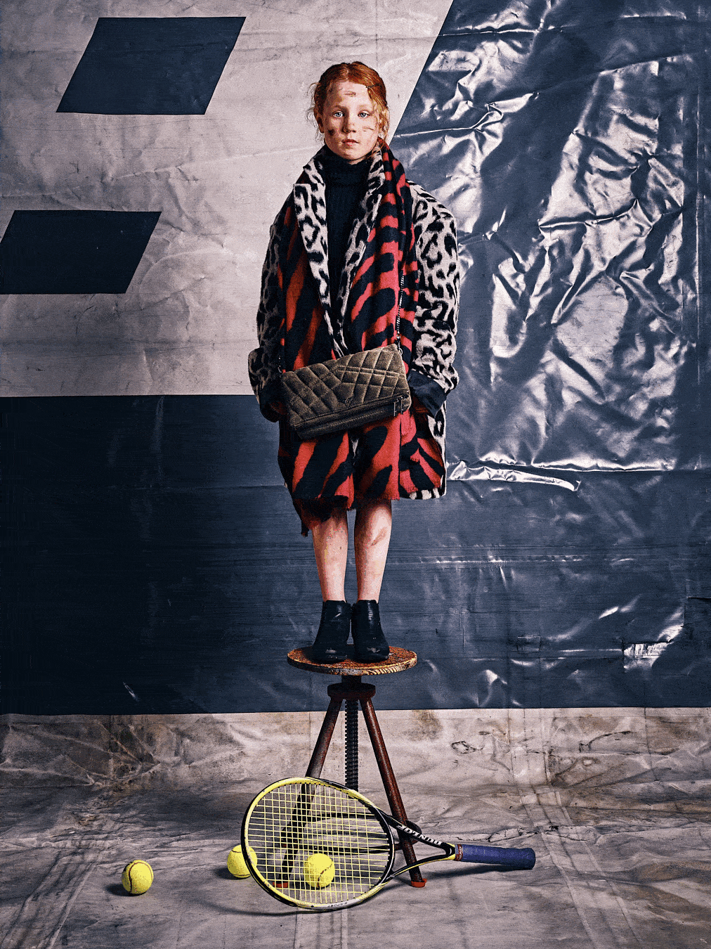 Two children in extravagant designer outfits posing with tennis props in an urban fashion editorial setting – photographed by Erik Bont