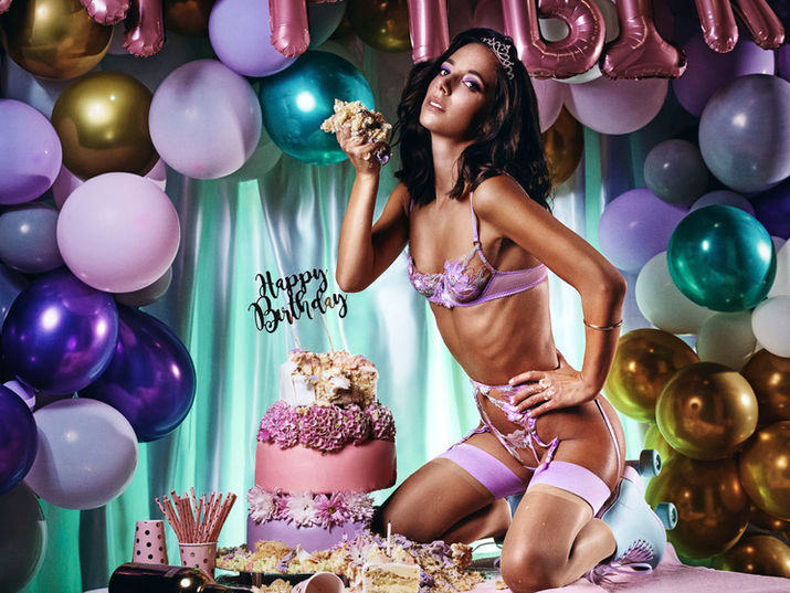 female model kneeling on a birthday table, cake in her hand