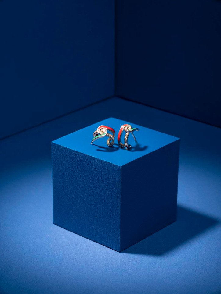 Designer earrings styled on a blue cube with dramatic lighting – conceptual product photo by Erik Bont