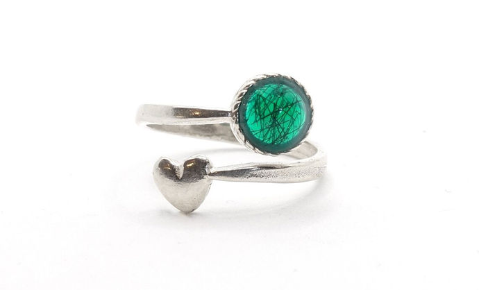 An adjustable Sterling silver ring with pet fur in green resin. The ring is shaped in a spiral with a round resin stone at one end and a silver heart on the other. The ring is photographed on a white background.
