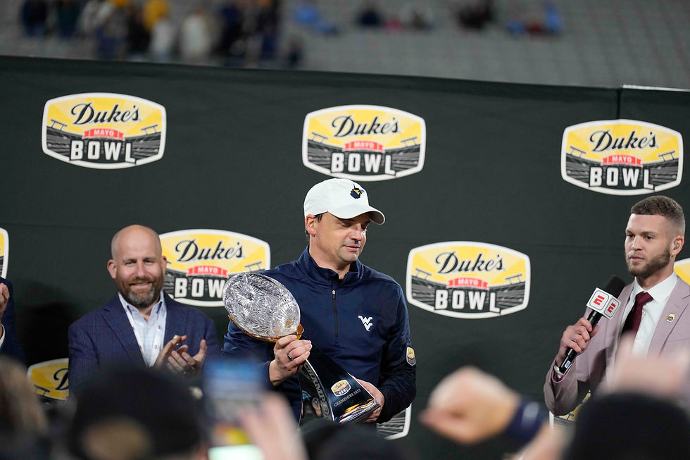 Neal Brown holding the Duke's Mayo Bowl trophy