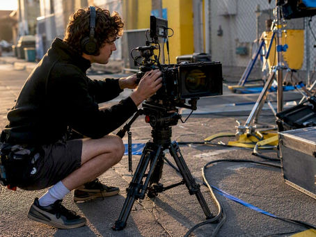 Camera assistant adjusting film camera on set
