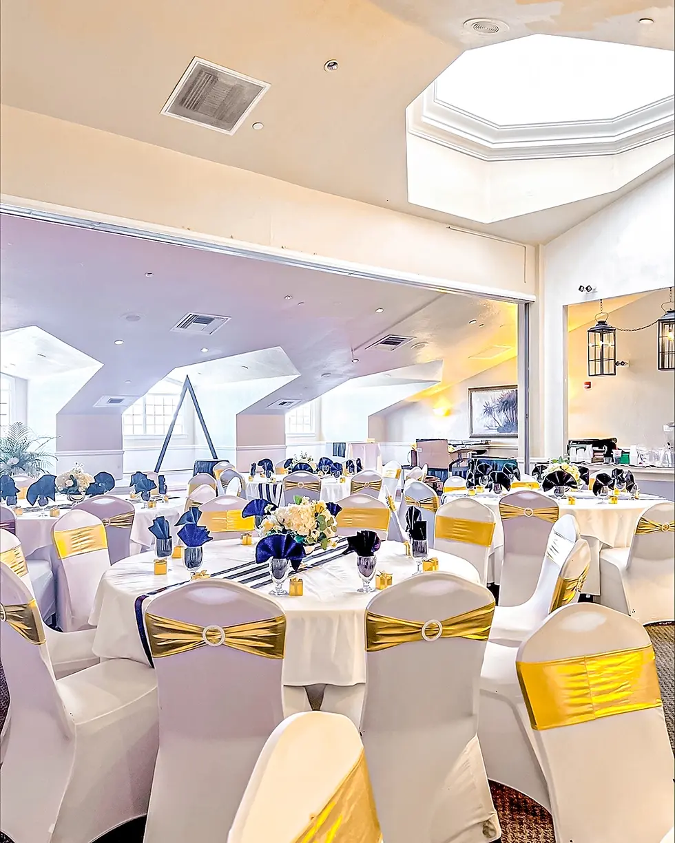 White chairs and tables with yellow sashes, decorated for an event.