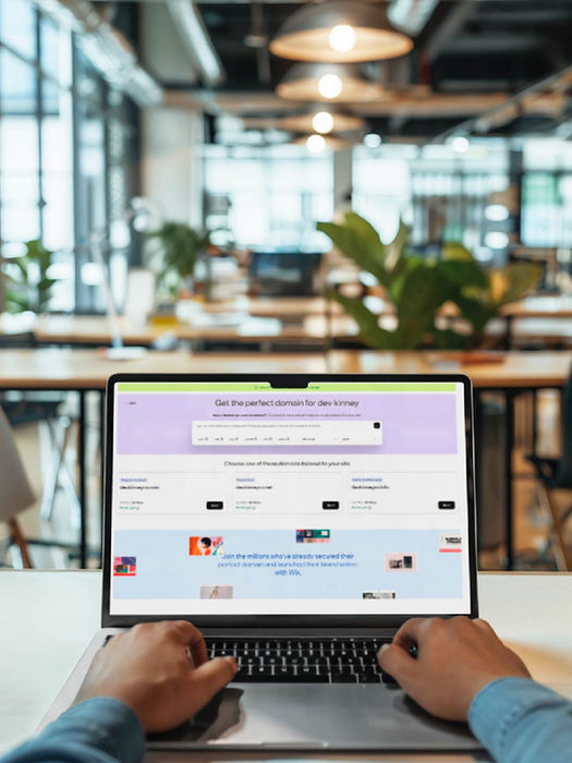 Person using computer, Website on display, blurry office background, working online.