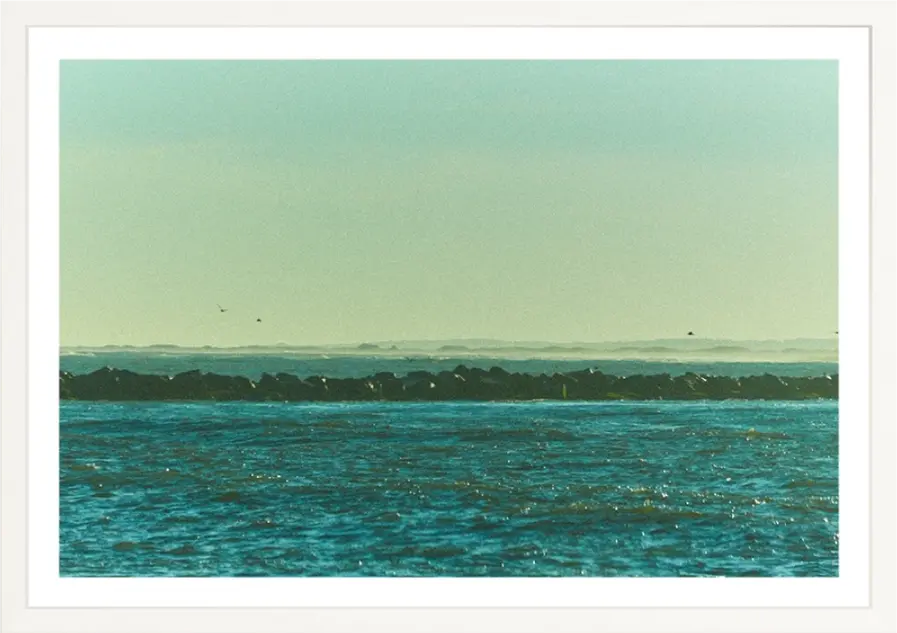 Distant shoreline across the tranquil blue water under a clear, hazy sky.