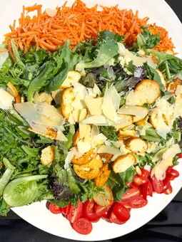 Fresh salad with mixed greens, carrots, tomatoes, and cheese.