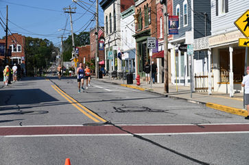 Runners on a town street lined with buildings