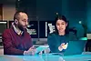 Two colleagues collaborate on a project, reviewing data on a laptop and tablet.