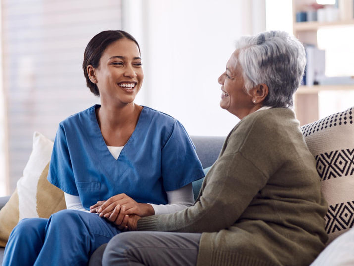 Caregiver and senior woman holding hands and smiling