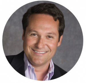 Smiling male team member wearing a blazer and collared shirt.