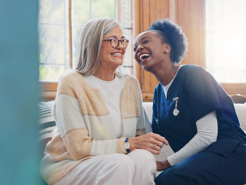 Caregiver and elderly woman laughing together