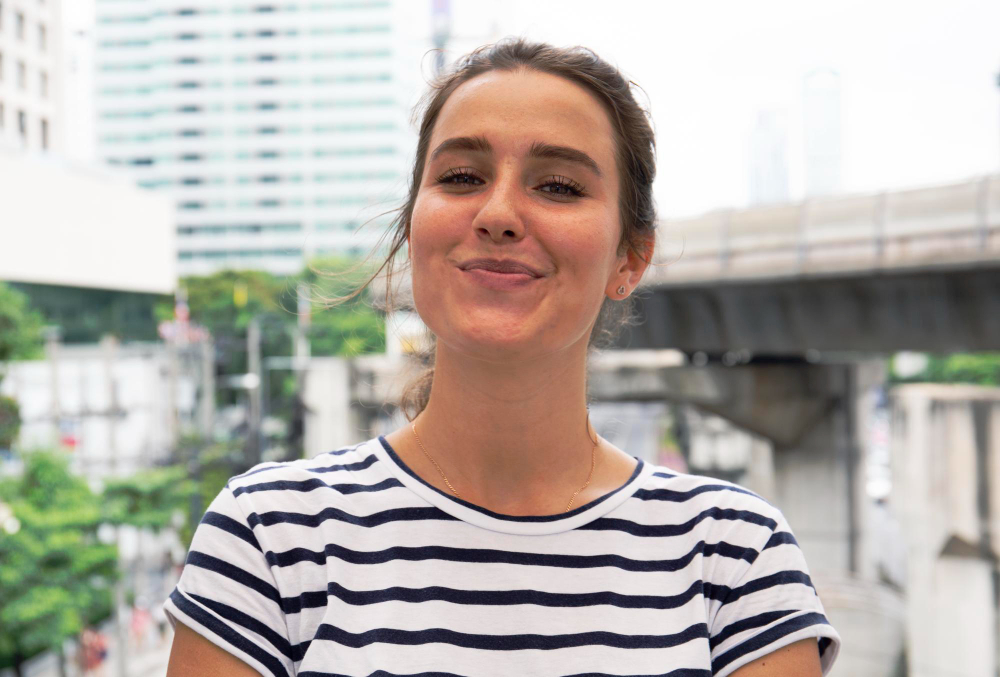 Smiling woman in striped shirt in front of city buildings