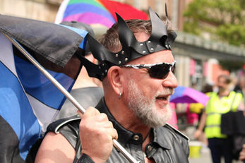 Person in a leather crown and vest at Pride Month parade.