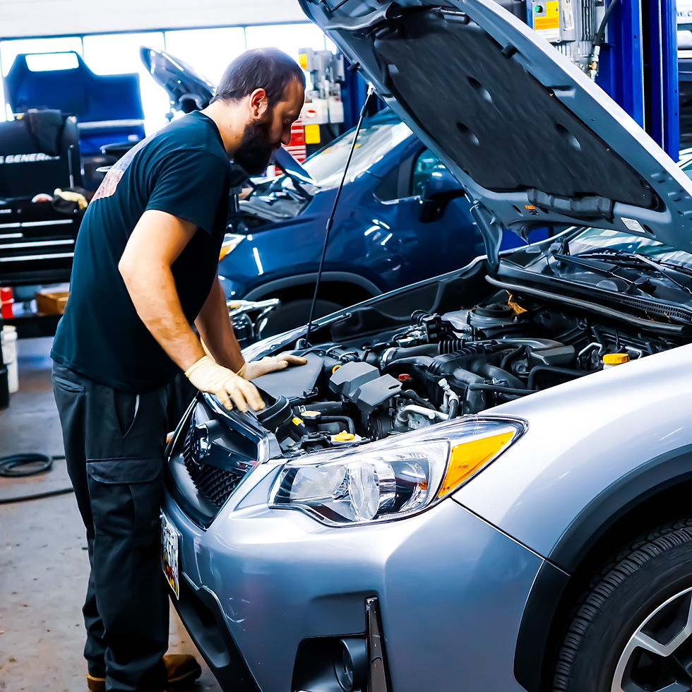 Mechanic in gloves inspects the engine of a silver SUV in a busy auto shop.