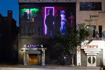Gatsby's sign, mural, and Strip's entrance with inviting light and Baltimore light beer.
