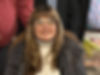 Woman with glasses, long hair, and a faint smile