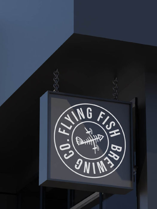 Flying Fish Brewing Co. sign on building corner, round logo, dark background.