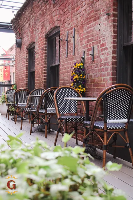 Outdoor patio with tables and chairs near a brick wall Guilford Hall Brewery