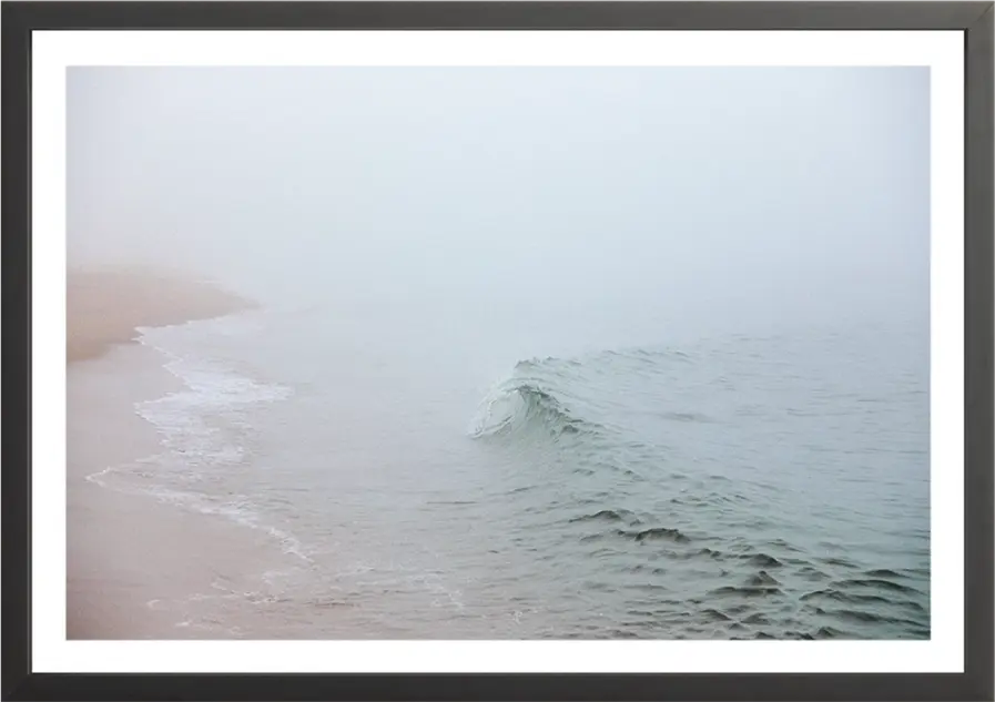 Misty ocean scene with waves crashing onto the shore in soft light.