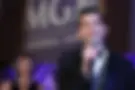 Man in tuxedo speaks into microphone at MGM National Harbor event.