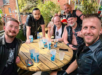 A group of men in leather gear socialising around a table during Pride Month.