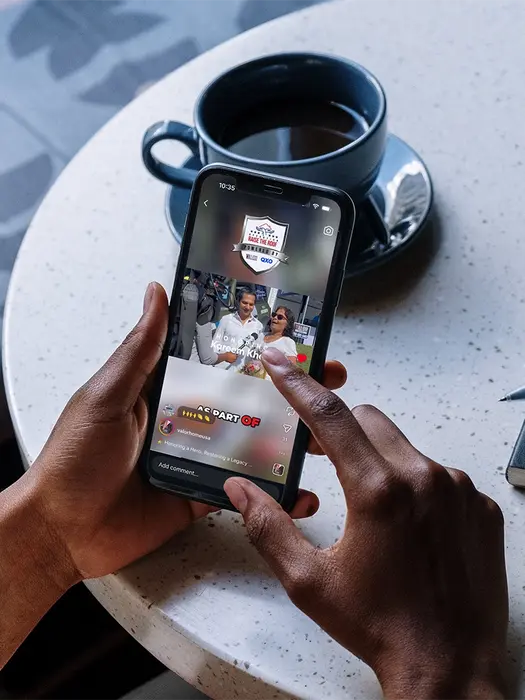 Person's hand using phone with picture on a table with coffee cup.